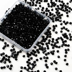 black beads in a plastic container on a white surface