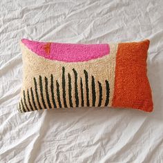 an orange and pink pillow sitting on top of a bed