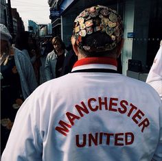 a man with a hat on his head is walking down the street in front of other people