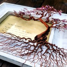 the tree is made out of wire and has been placed on top of an old book