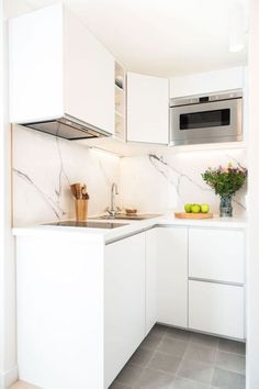 a kitchen with white cabinets and marble counter tops, along with a microwave above the sink