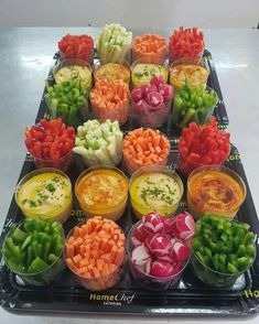 many different types of vegetables are arranged in plastic cups on a tray, ready to be eaten