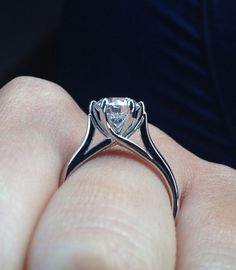 a close up of a person's hand holding a ring with a diamond in it