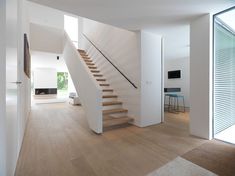 there is a stair case in the middle of this living room with white walls and wood flooring