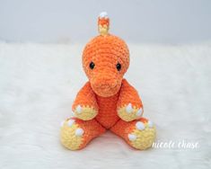 an orange crocheted stuffed animal sitting on top of a white fur covered floor