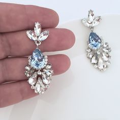 "Elegant Vintage style Bridal Earrings. Made with high-quality Crystal rhinestones in light blue and clear crystals. Gorgeous and elegant floral-inspired drops. Pair them with a cocktail dress or an over-sized sweater for an everyday look. Rhodium silver plated 2\" length, 1\" width Glass crystals Surgical steel posts, hypoallergenic" Blue Cubic Zirconia Chandelier Earrings For Party, Elegant Light Blue Crystal Earrings For Party, Blue Crystal Teardrop Bridal Earrings, Blue Crystal Dangle Bridal Earrings, Blue Crystal Earrings For Wedding, Blue Crystal Bridal Earrings, Blue Crystal Bridal Earrings With Matching Set, Blue Rhinestone Crystal Earrings For Wedding, Light Blue Dangle Crystal Earrings For Party