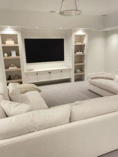 a large white couch sitting in front of a flat screen tv mounted on a wall