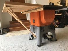 an orange and black machine sitting on top of a wooden table next to a stair case