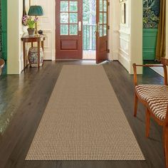 a large hallway with wooden floors and green walls, two doors leading to another room