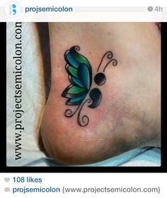 a small butterfly tattoo on the side of a person's foot, which is black and green