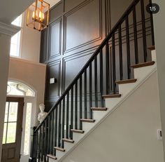 a staircase leading up to an open door with two chandeliers hanging from the ceiling