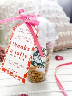 a starbucks coffee cup with a thank you tag attached to it and some candy in the background