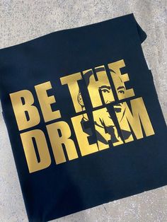 a t - shirt with the words be the dream on it is laying on concrete