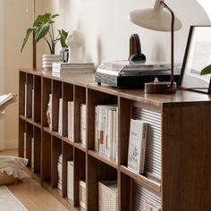 a bookshelf filled with lots of books next to a lamp on top of a table