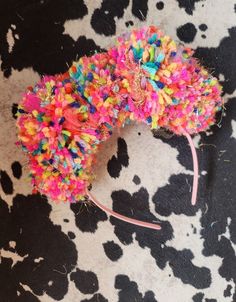 a colorful mouse headband on top of a cow print surface with lots of colored sprinkles