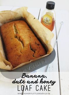 banana, date and honey loaf cake in a pan next to a bottle of honey