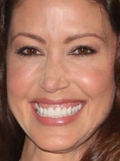 a close up of a woman smiling at the camera with brown hair and white teeth