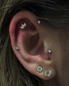 a close up of a person wearing ear piercings with three small diamonds on them