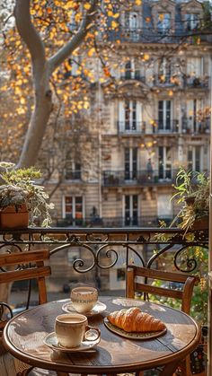 a table with coffee and croissants on it in front of a window