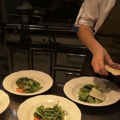 four plates with food on them being prepared by a chef in a restaurant or kitchen