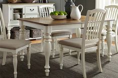 a dining room table with chairs and a bowl of fruit on top of the table