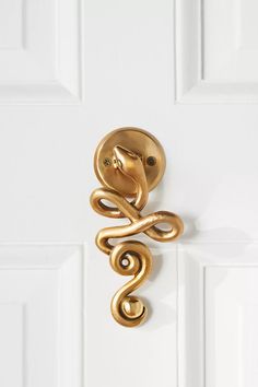 a door handle with a snake design on it's side, hanging from a white door