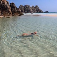 a person swimming in the ocean near some rocks