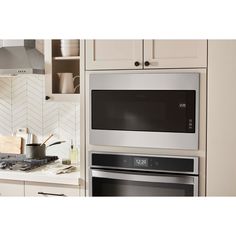 a microwave oven built into the wall in a kitchen with white cabinets and counter tops