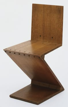 a wooden chair sitting on top of a white surface with holes in the back and sides