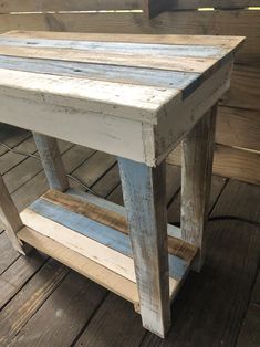 an old wooden table is painted white and blue with wood planks on the floor