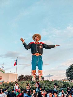 a large statue of a man wearing a cowboy hat and holding his arms out