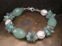 This luxurious bracelet is made with gorgeous faceted Chalcedony in combination with Karen Hill Tribe Michelia flowers and clusters of Apatite, Chrysoprase and Quartz. Cute detail: a tiny Sterling Conch Shell dangle. The bracelet closes with a Sterling silver lobster claw and is ready to ship. Length approx. 21,5cm/8.45inch, fits a 17cm/6.5inch wrist perfectly. Wear this gorgeous piece of jewellery on any special occassion. You can find more of our bracelets here: https://www.etsy.com/nl/shop/Vo Cluster Bracelet, Diy Jewelry Inspiration, Cluster Bracelets, Green Chalcedony, Hill Tribe Silver, Sea Green, Etsy Jewelry, Boho Bracelets, Conch