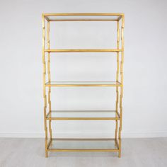 a gold metal shelf with glass shelves on each side and white walls in the background