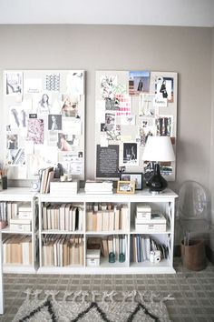 a white book shelf with books and pictures on the wall next to a lamp in a living room