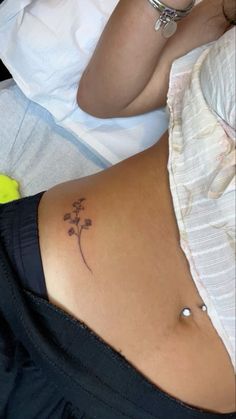 a woman's stomach with a small flower tattoo on her lower back and side