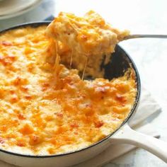 a close up of a spoon in a casserole dish with cheese on top