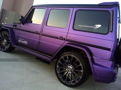 a purple mercedes g - class is parked in front of a building