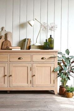 a wooden dresser sitting next to a potted plant on top of a hard wood floor