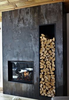 a fireplace with firewood stacked in front of it next to a wall mounted heater