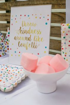 a table topped with lots of candy next to a white bowl filled with marshmallows