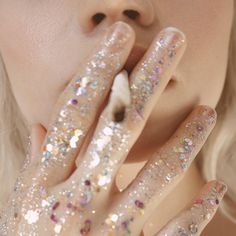 a close up of a person with glitter on their hands and fingers in front of her face