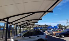 several cars are parked under the awnings in a parking lot at a gas station