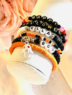 "This cute little Halloween stacking bracelet set contains a custom name bracelet and  looks great with all of your Halloween costumes! Fun and colorful, personalized with your name in style #3. A mixture of orange and black, with a little of white and then an adorable enamel ghost to finish it off.  These bracelets can be mixed and matched, or purchased as a full set of 6 stackable Halloween bracelets.  Bracelet #1 - orange \"Heishi\" beads Bracelet #2 - colorful 6mm glass beads with \"Happy\" Clay Bead Halloween Bracelet Ideas, Bead Bracelet Stack Ideas, Cute Halloween Bracelet Ideas, Halloween Bracelets Clay Beads, Diy Halloween Bracelets, Halloween Clay Bracelets, Halloween Bead Bracelet, Halloween Stretch Bracelets, Autumn Clay Bracelets