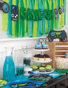 a table topped with cupcakes and cake covered in frosting next to green streamers