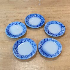 four blue and white plates sitting on top of a wooden table