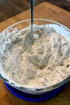 a blue bowl filled with cream cheese on top of a wooden table