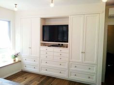 a bedroom with white cabinets and a flat screen tv mounted on it's wall