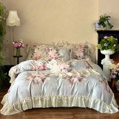 a bed with flowers on it in a room next to a fireplace and potted plants