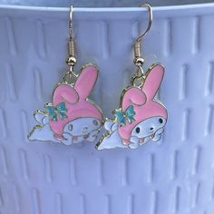 pair of pink bunny earring with green bow on white plated surface next to blue bowl