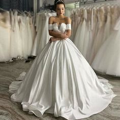 a woman is standing in front of some wedding dresses